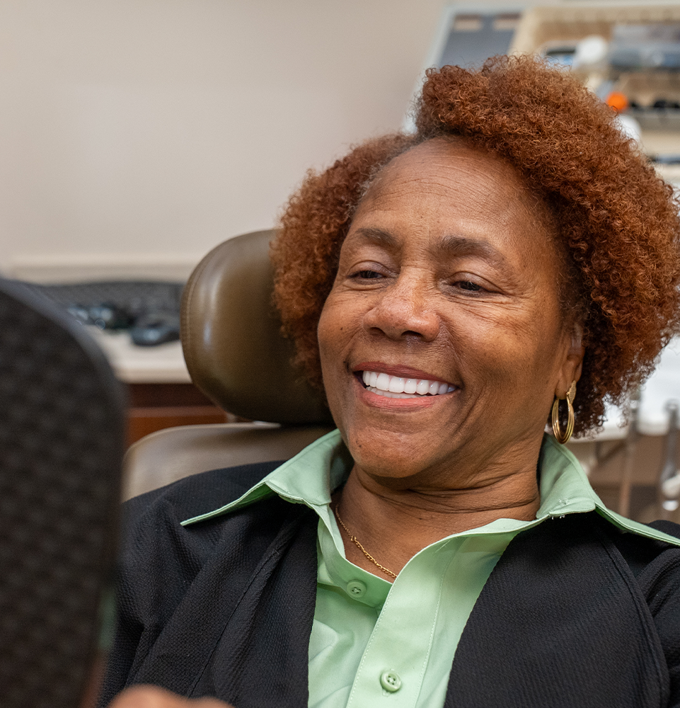 female patient smiling into a mirror at the office
