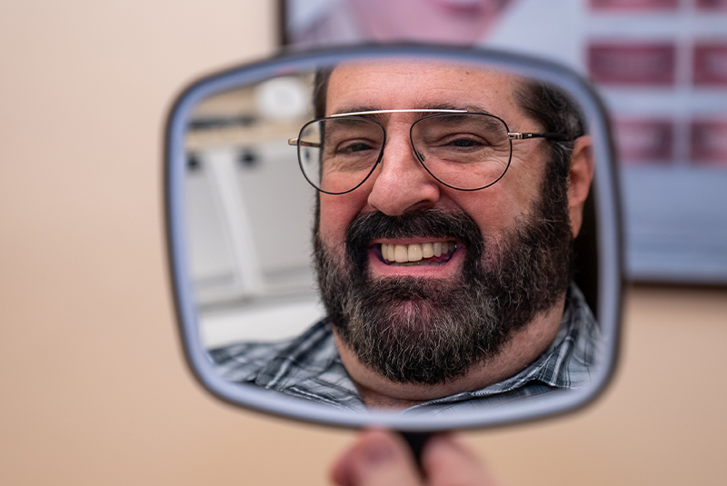 Dr. Philip's patient smiling into a mirror he is holding